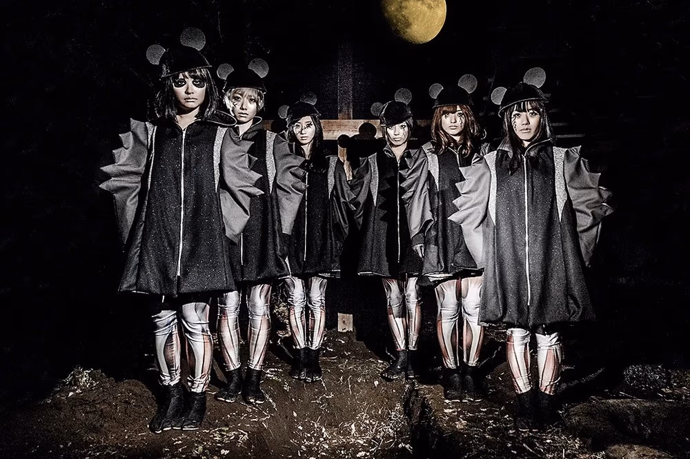 BiS con atuendos de color negro y de mangas arrugadas, usando orejas tipo Mickey Mouse, y posando en una especie de cementerio a la luz de la luna, frente a una cruz.